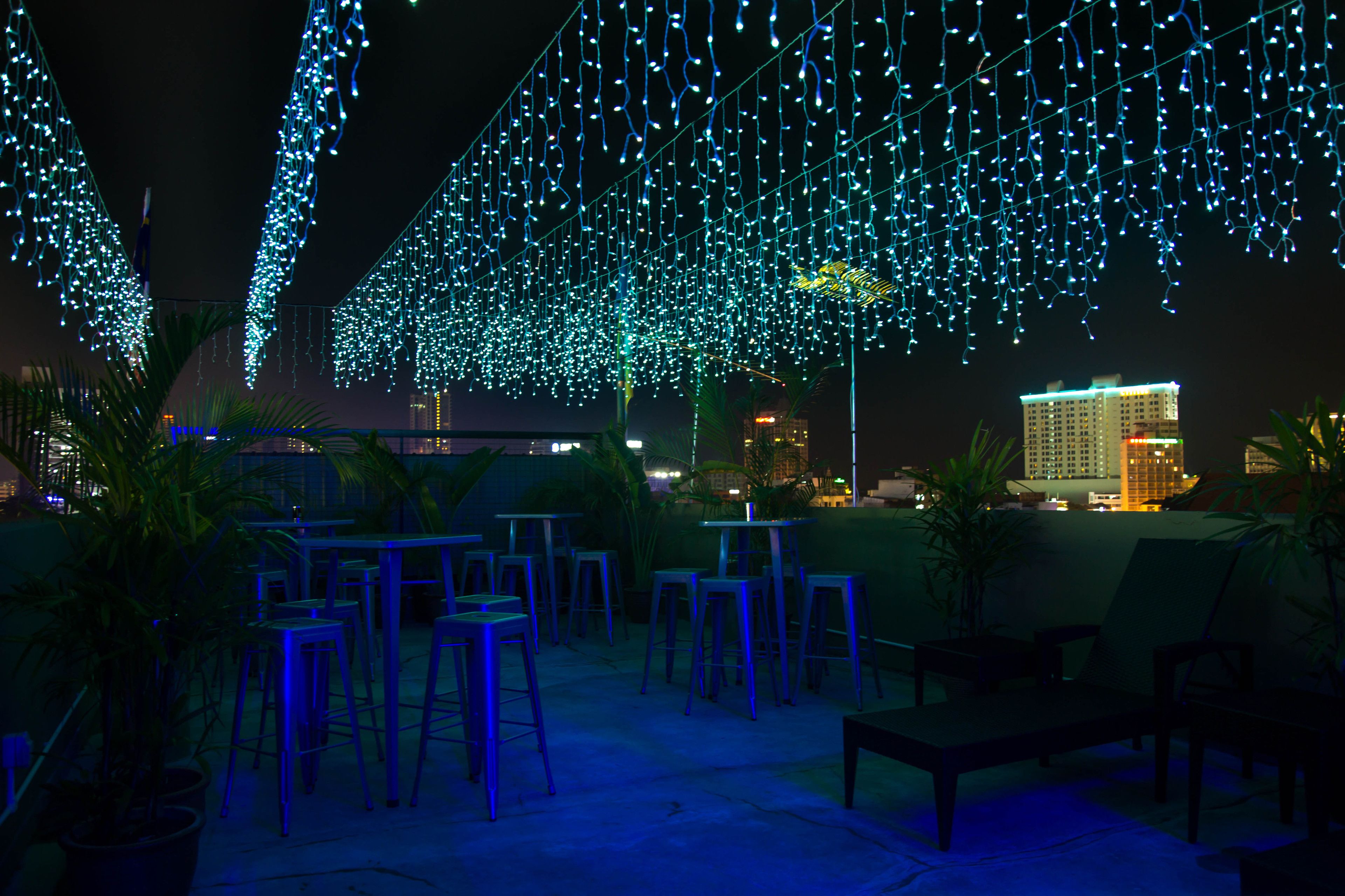 An outdoor seating area with tables and chairs, decorated with string lights.