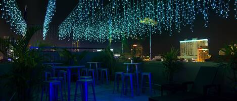 An outdoor seating area with tables and chairs, decorated with string lights.
