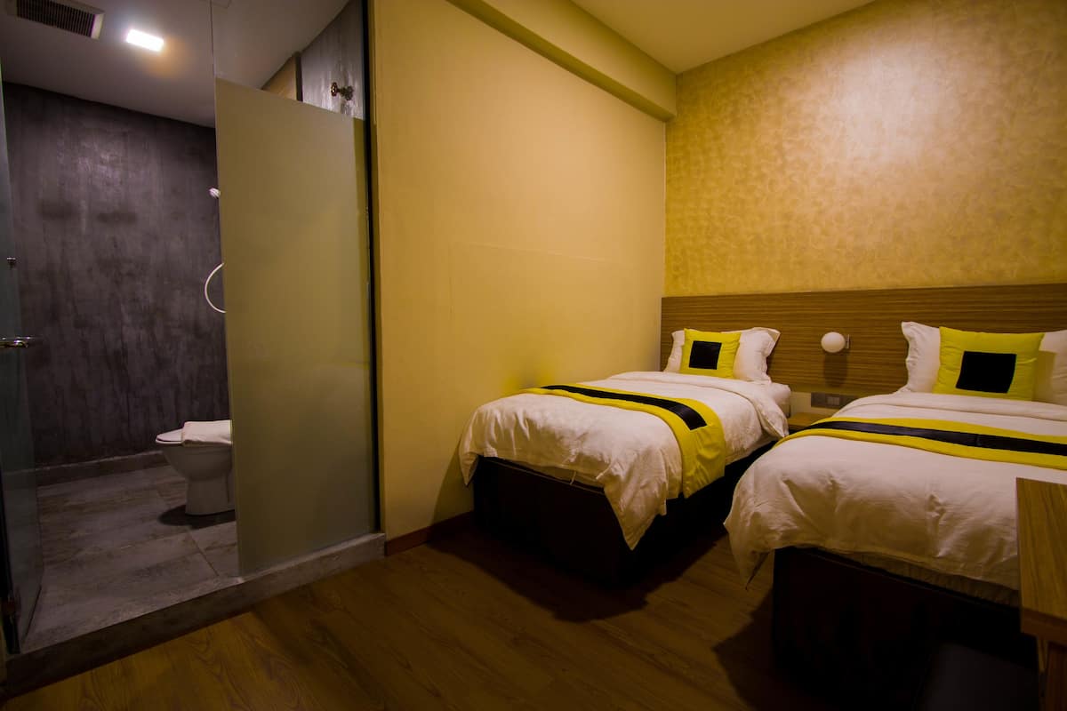 Een hotelkamer met twee bedden, een houten hoofdbord, een douche en een toilet.