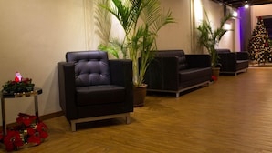 A modern lobby with leather sofas, a large palm tree, and a decorated Christmas tree.