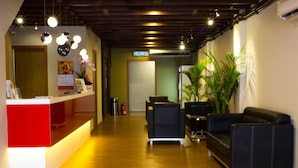 A reception area with a red counter, black leather sofas, and a wooden floor.