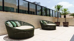 A rooftop terrace with wicker furniture and potted plants. - Athos Bulcão Hplus Executive (Brasília)