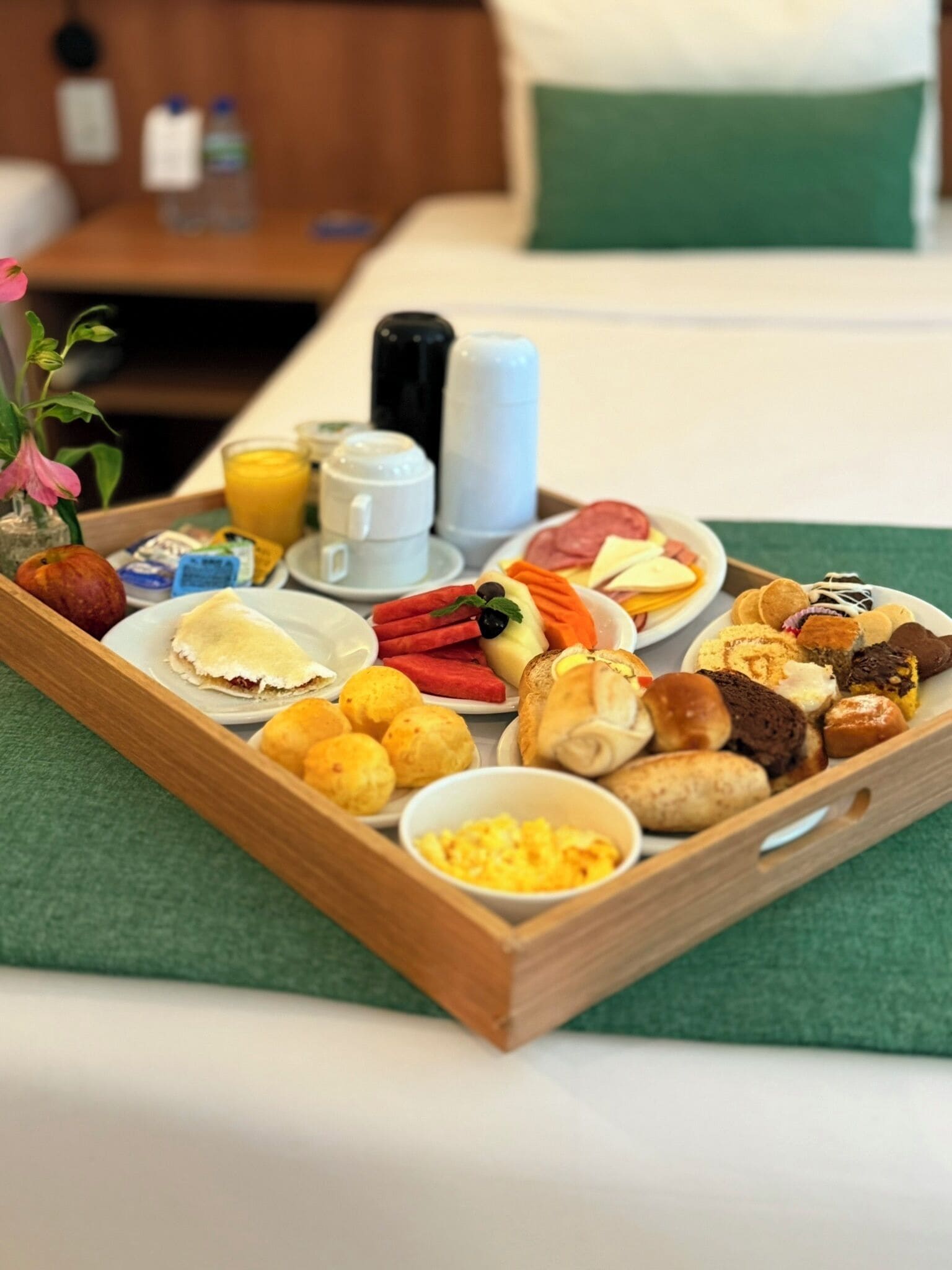 Una bandeja de desayuno con diferentes alimentos y bebidas sobre una cama.