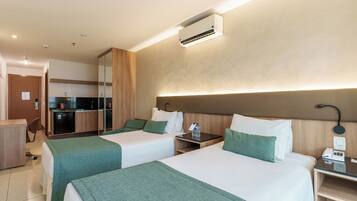 Habitación de hotel con dos camas, un escritorio, una silla, un minibar y un baño.