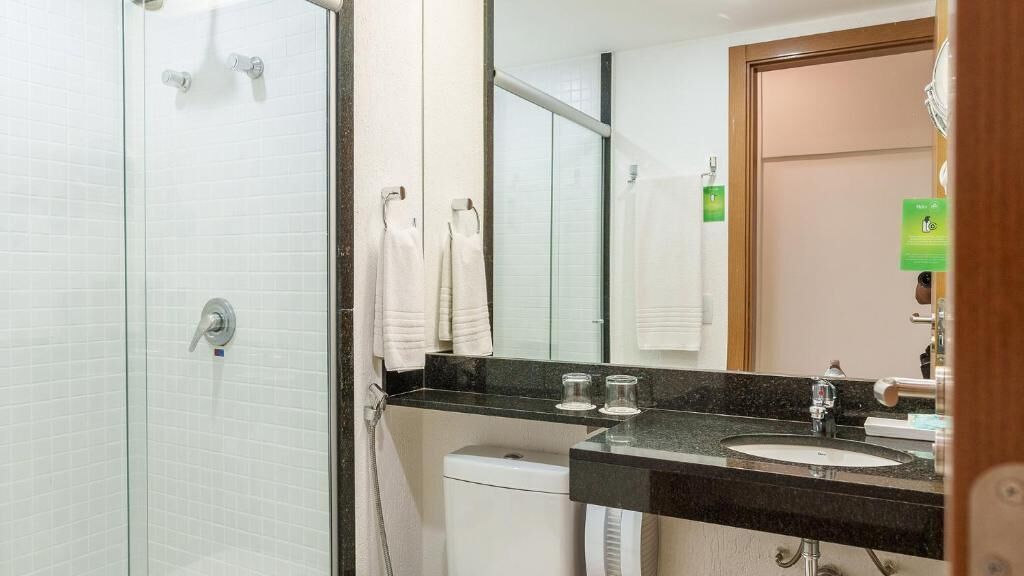 A bathroom with a glass shower enclosure, a sink with a mirror, and a toilet.