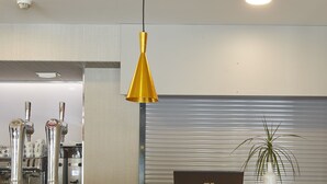 A modern reception desk with a laptop, a yellow pendant light, and a potted plant. - Hotel Iriguibel (Huarte)