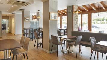 A modern restaurant interior with wooden flooring, high tables, and comfortable seating.