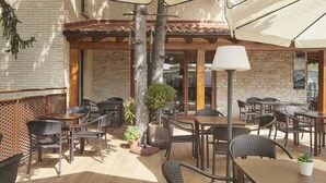 An outdoor patio area with wicker furniture, potted plants, and a lamp. - Hotel Iriguibel (Huarte)