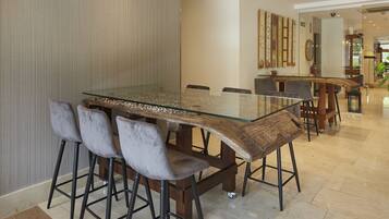A modern dining area with a glass-top table, bar stools, and a wooden accent.
