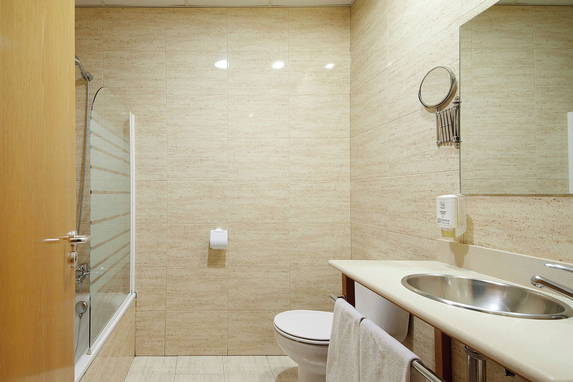 A bathroom with a shower, toilet, sink, and a mirror.