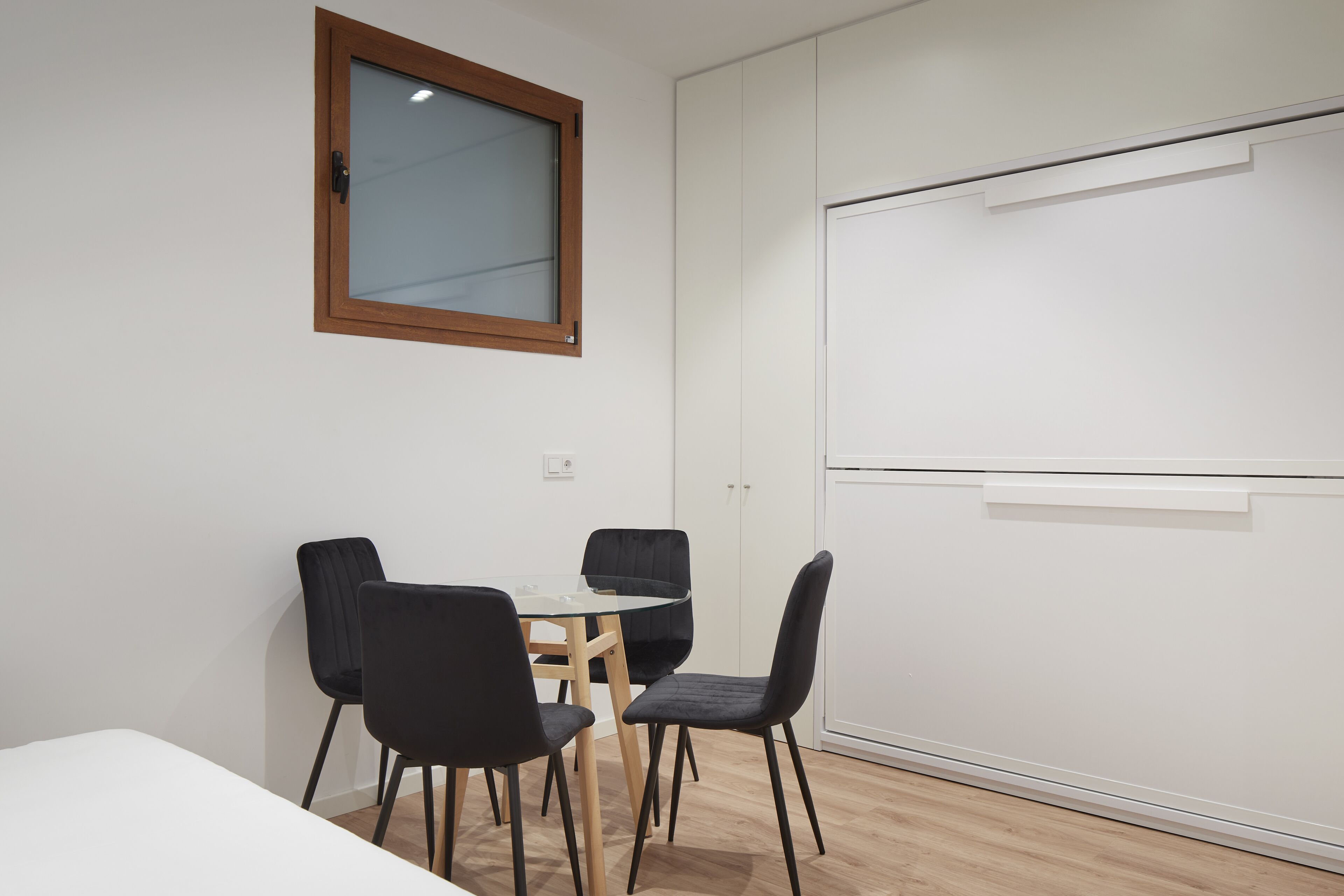 A conference room with a whiteboard, a wooden-framed window, and a table with four chairs.