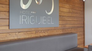 A modern hotel interior with a wooden wall, a gray bench, and a table. - Hotel Iriguibel (Huarte)