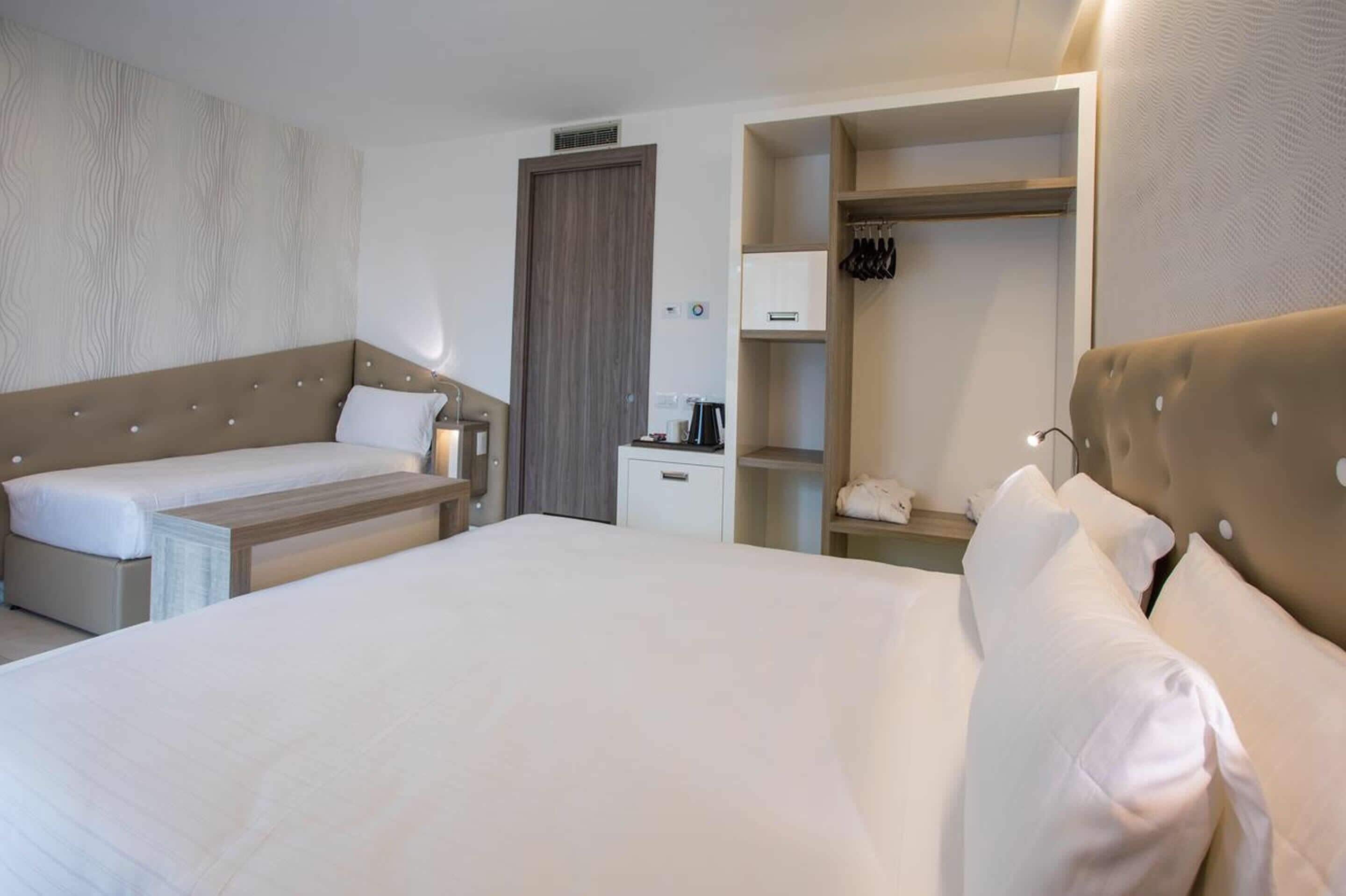 Une chambre d’hôtel avec un grand lit, un canapé-lit, une armoire et un bureau équipé d’une bouilloire.