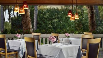 A restaurant with tables set for dining, wooden chairs, and hanging pendant lights.