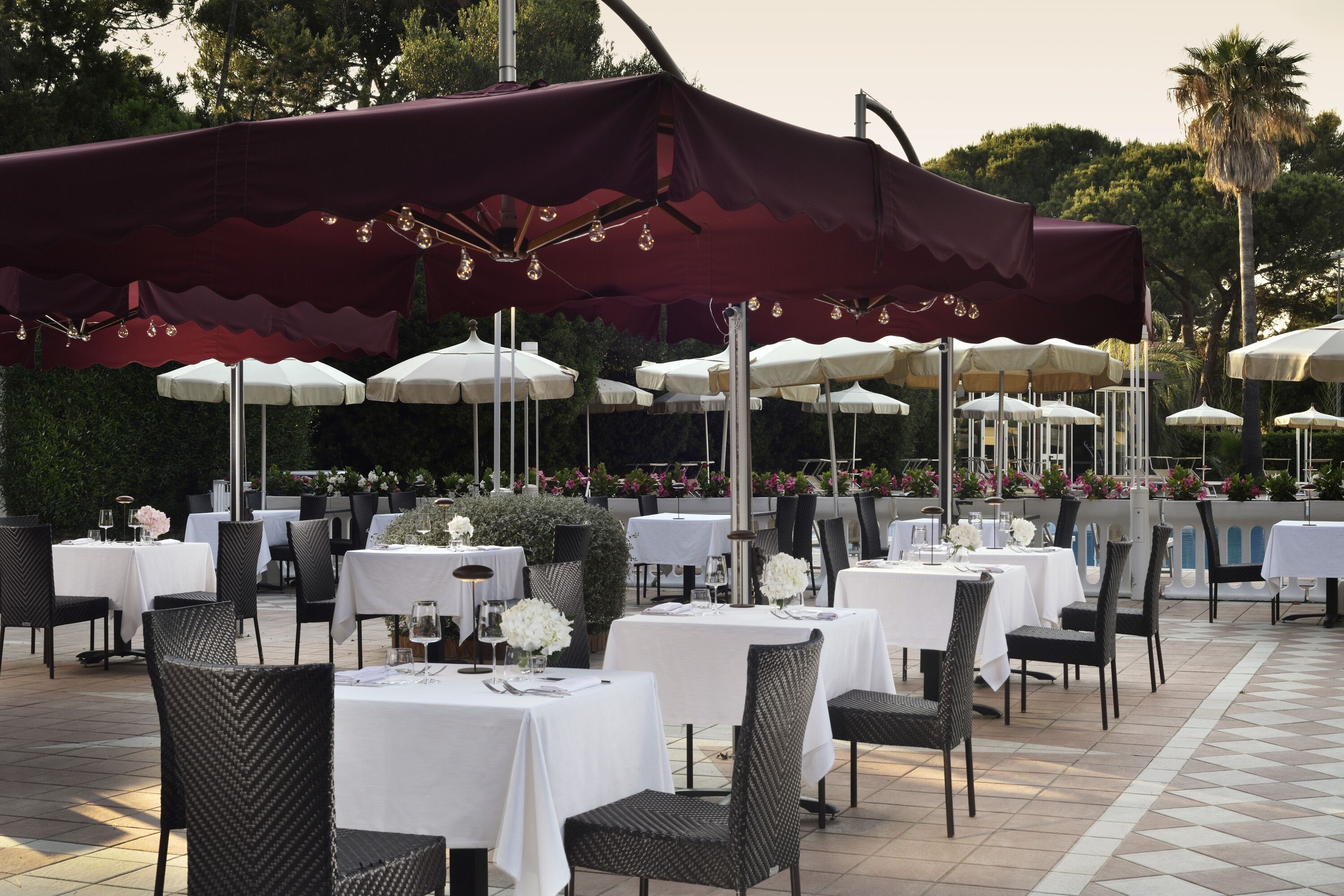 Un espace extérieur aménagé pour les repas, avec des tables et des chaises, protégé par des parasols.