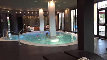 Relax by the oval-shaped pool surrounded by lounge chairs and large windows offering a view of the outdoors.