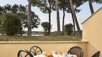 A table set for breakfast with a view of trees and a fence.