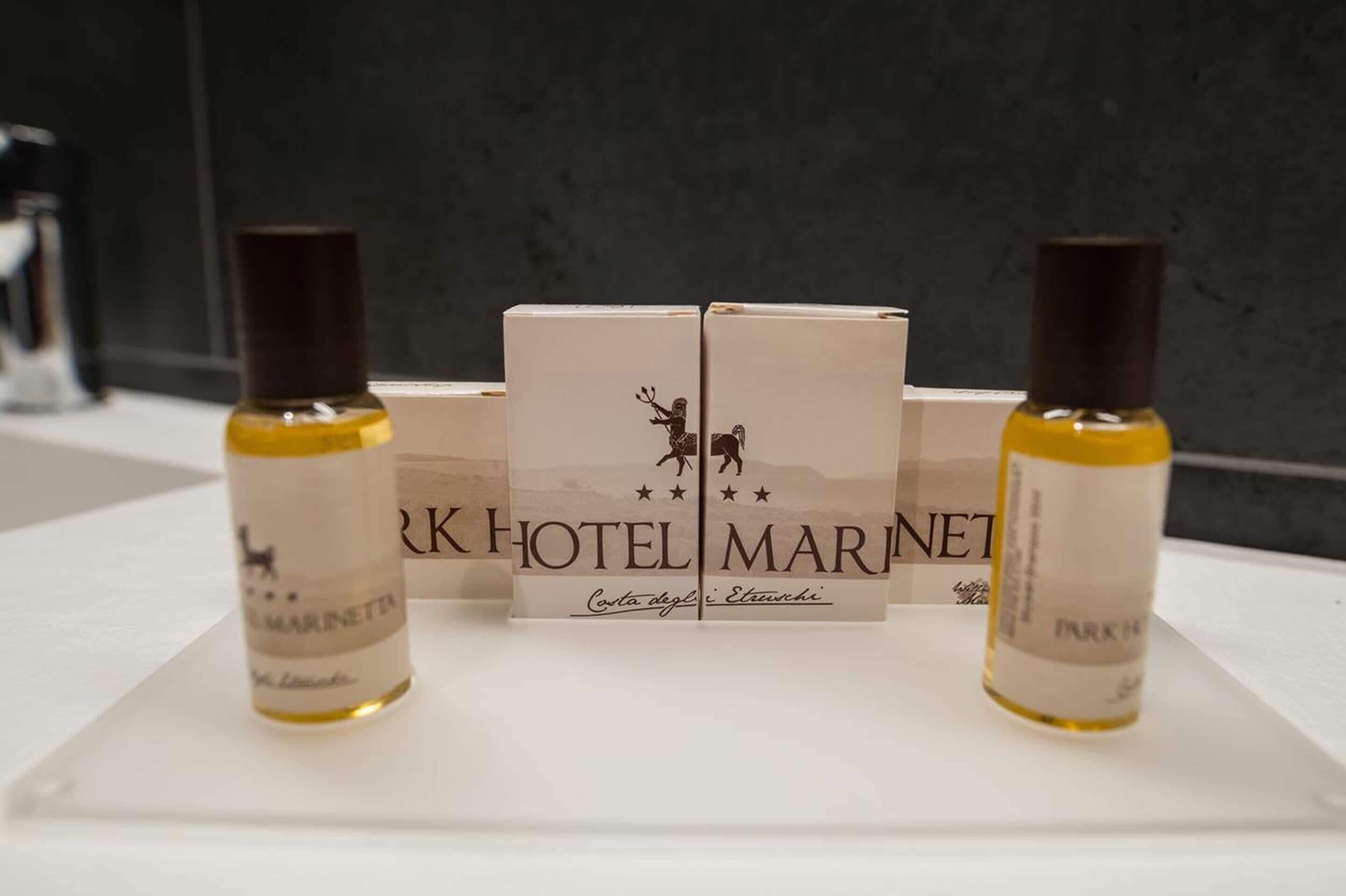 A hotel room with a white table displaying two bottles of perfume and two boxes with the hotel name.