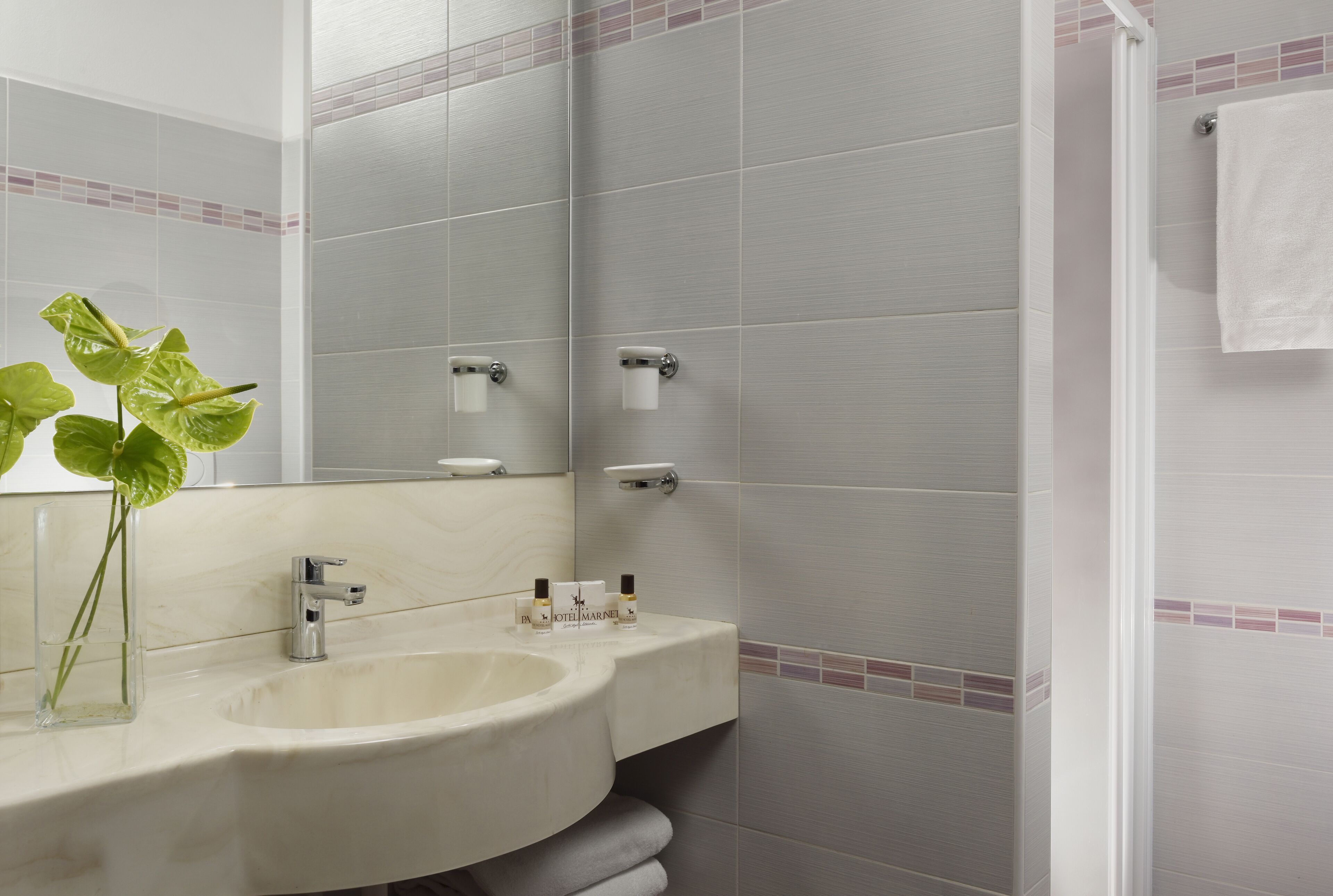 Un baño con lavamanos, espejo y toallero.