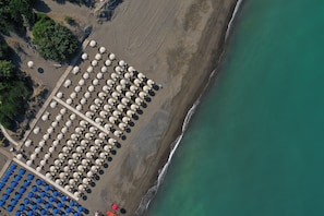 An aerial view of a beach with rows of umbrellas and sun loungers.