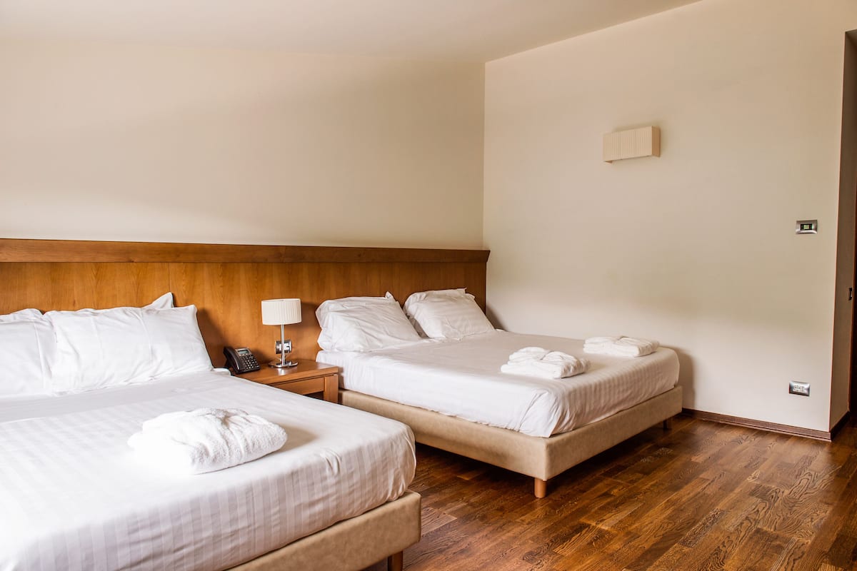 Ein Hotelzimmer mit zwei Betten, einem Holzkopfteil, Nachttischlampen und einem Telefon.