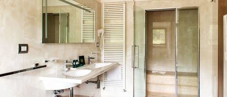 A modern bathroom with two sinks, a large mirror, and a glass-enclosed shower.