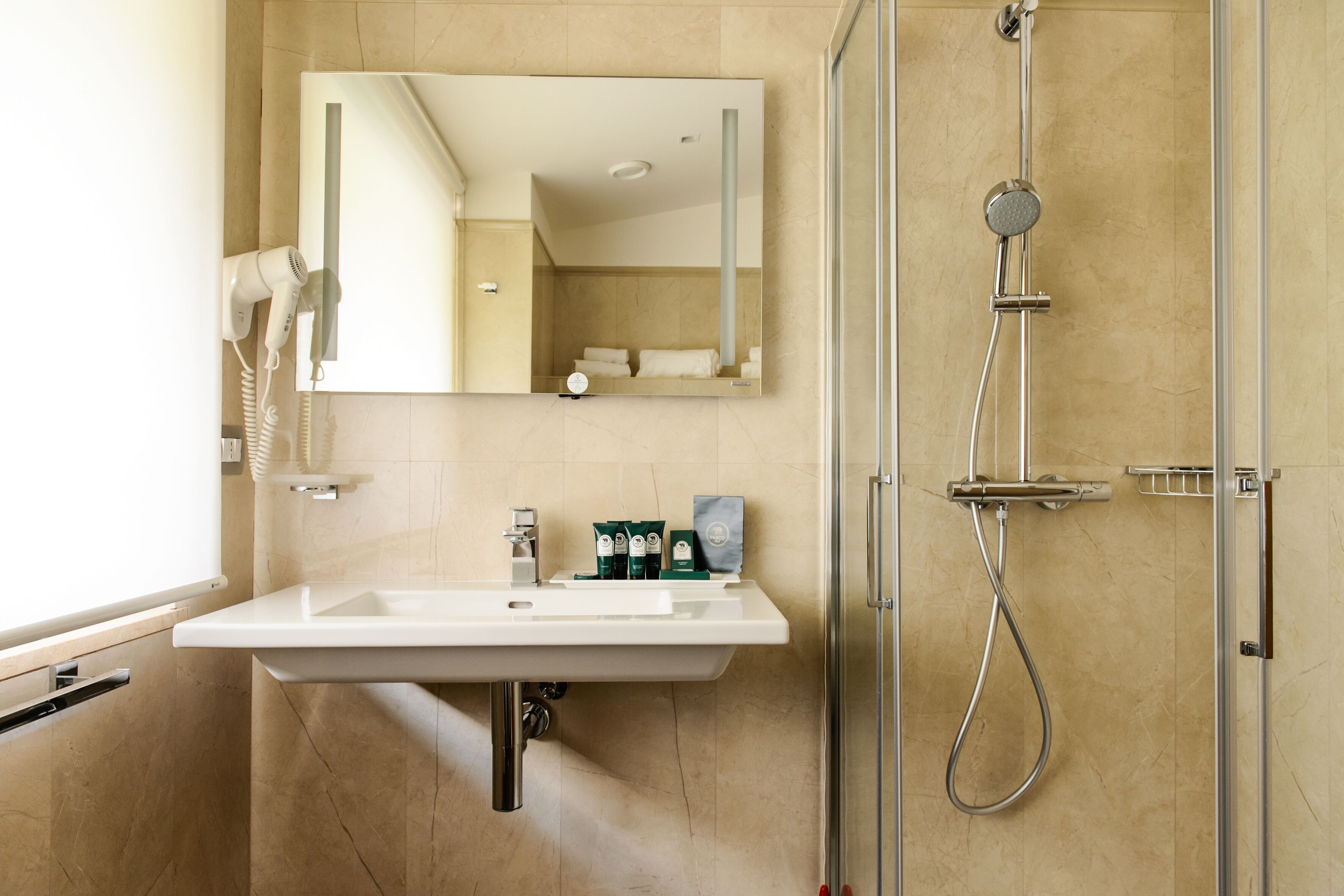 Une salle de bain moderne avec un lavabo blanc, un miroir et une douche à parois de verre.