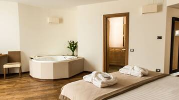 Ein modernes Hotelzimmer mit einem großen Bett, einer Badewanne, einem Sessel und Holzboden.
