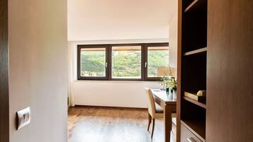 Une pièce dotée d’un plancher en bois, d’une table à manger avec des chaises, d’une fenêtre donnant sur un paysage verdoyant et d’une armoire intégrée.