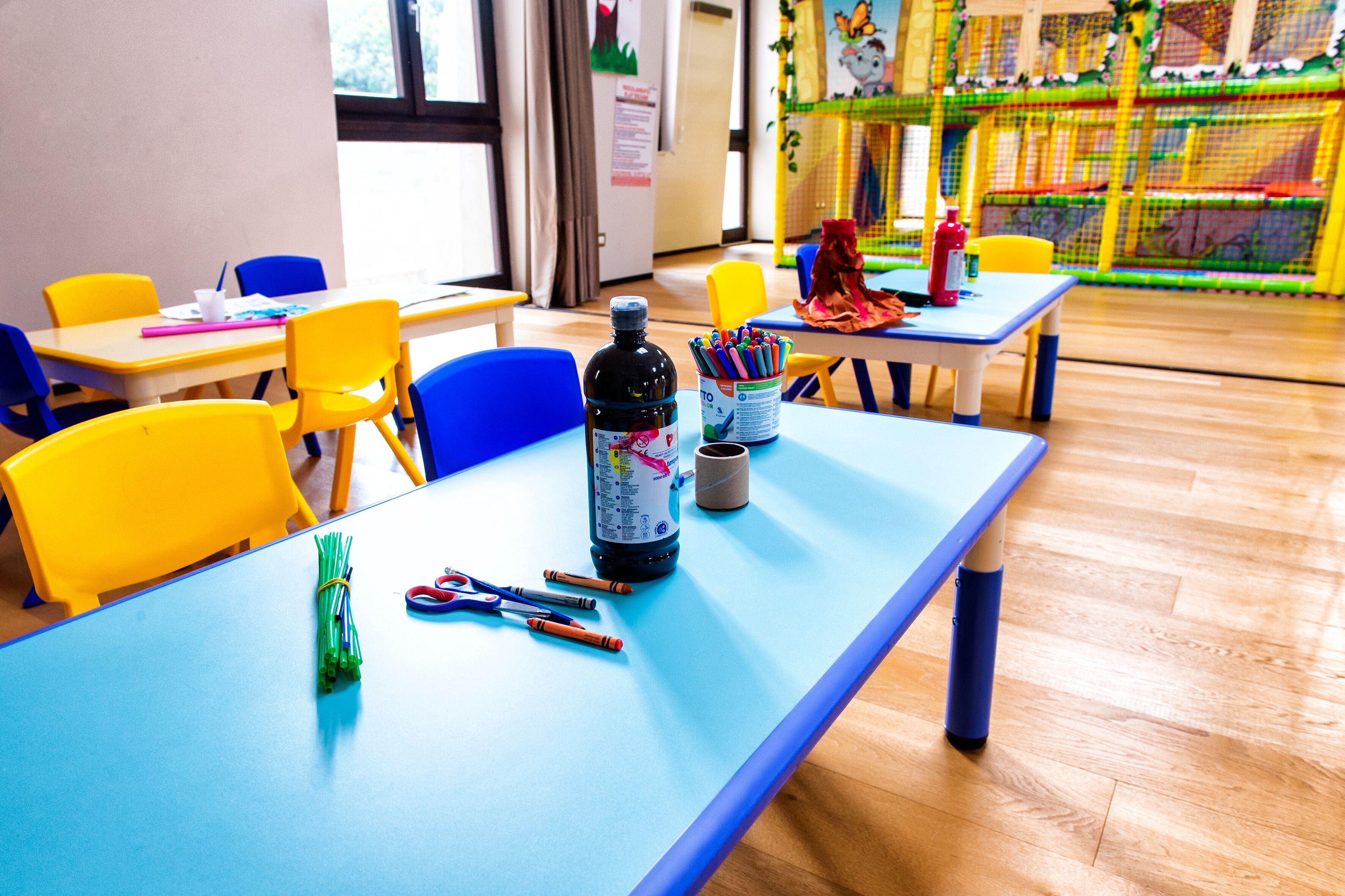Un aula con sillas, mesas y material educativo de colores.