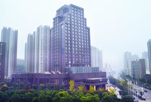 A high-rise building with a modern architectural design, surrounded by other tall buildings and a dense urban environment. - Days Hotel & Suites by Wyndham Hengan Chongqing (Chongqing)