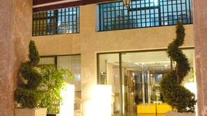 L’entrée du restaurant Le Marius, une brasserie moderne dotée d’une façade en verre et agrémentée de deux plantes en pot.
