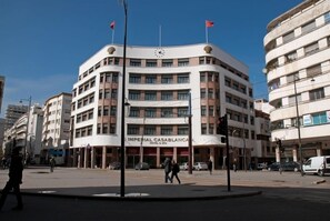 Un hotel de varios pisos con fachada curva, múltiples balcones y un reloj en la parte superior.