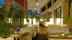 Un restaurant avec des banquettes en cuir blanc, des tables en bois et des plantes en pot.