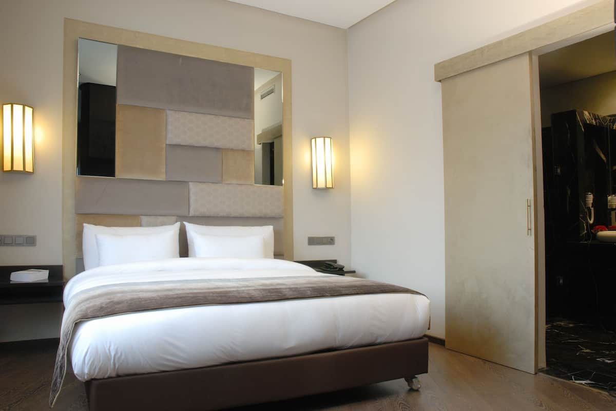 Una habitación de hotel moderna con una cama grande, un espejo y dos luces fijadas a la pared.