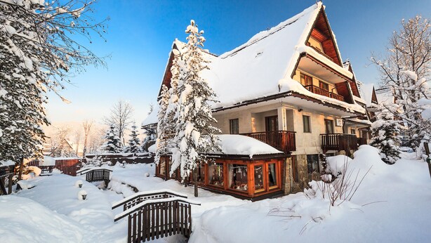 A snow-covered chalet with a balcony, surrounded by snow-laden trees and a wooden fence. - Czarny Potok Wellness & Spa Zakopane Centrum (Zakopane)