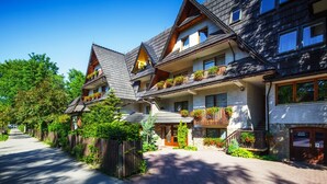 A row of traditional chalet-style buildings with multiple balconies, wooden facades, and a clear sky. - Czarny Potok Wellness & Spa Zakopane Centrum (Zakopane)
