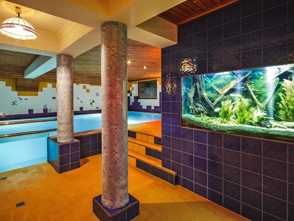 Área de piscina com um grande aquário e paredes revestidas de azulejos.
