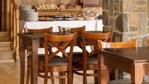 A dining area with wooden furniture, a stone wall, and a painting on the wall. - Czarny Potok Wellness & Spa Zakopane Centrum (Zakopane)
