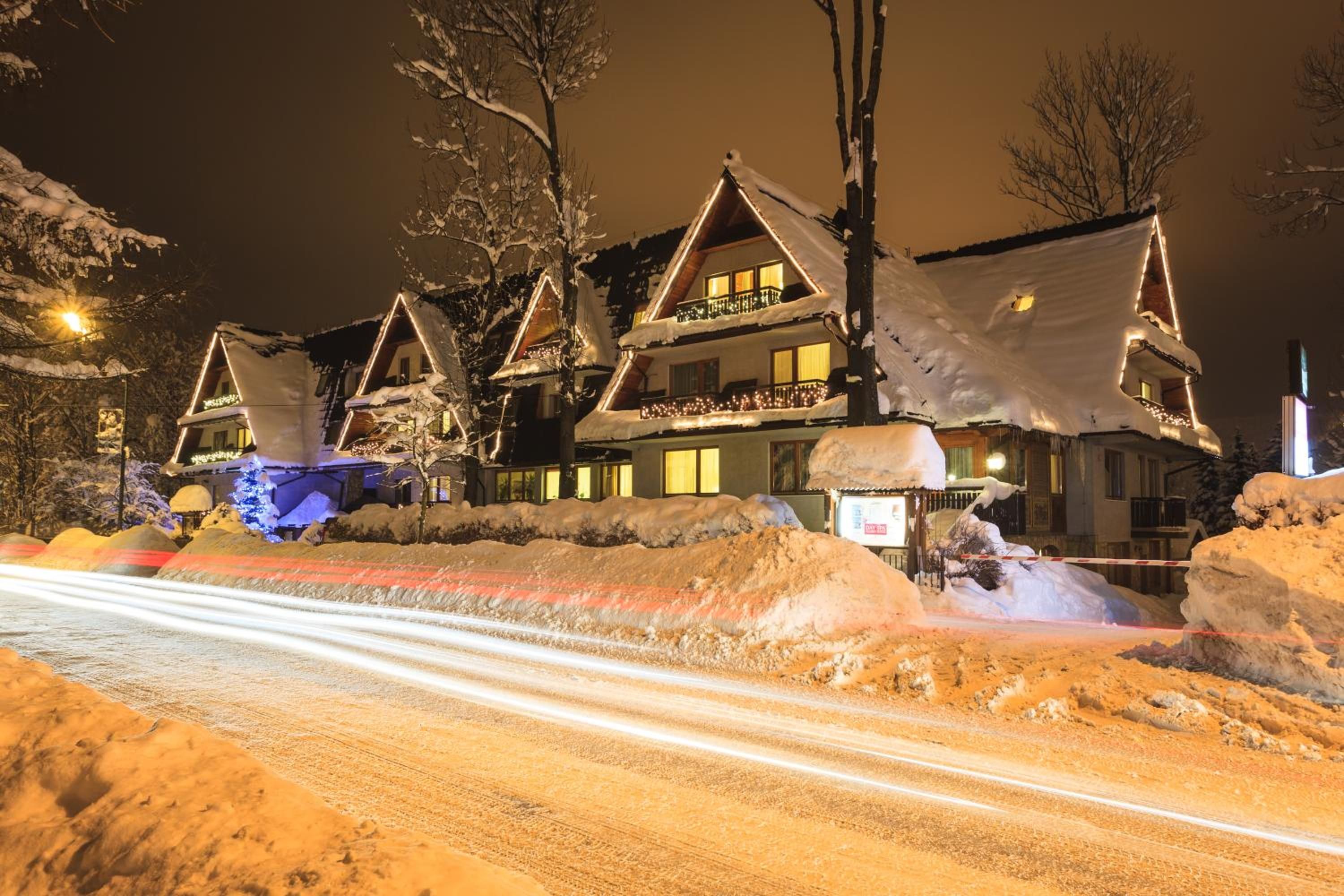 A multi-story building with snow-covered roofs and balconies, surrounded by snowbanks.