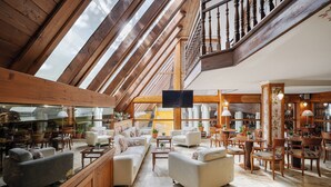 A spacious, high-ceilinged lounge with wooden beams, comfortable seating, and a large TV screen. - Hotel Belvedere Resort & SPA (Zakopane)