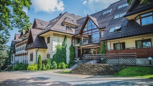 A row of traditional European-style buildings with steeply pitched roofs, large windows, and a cobblestone pathway leading to a stone staircase. - Hotel Belvedere Resort & SPA (Zakopane)