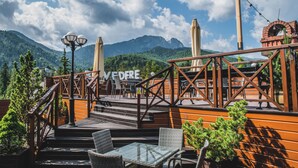 A wooden deck with outdoor seating, a sign reading "VFDERE," and a mountainous backdrop. - Hotel Belvedere Resort & SPA (Zakopane)