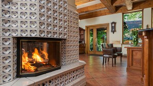A fireplace with a tiled surround, a wooden ceiling, and a view of the outdoors through a door. - Hotel Litwor (Zakopane)