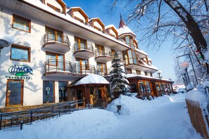 A hotel with multiple balconies, a snow-covered entrance, and a clear blue sky. - Hotel Litwor (Zakopane)