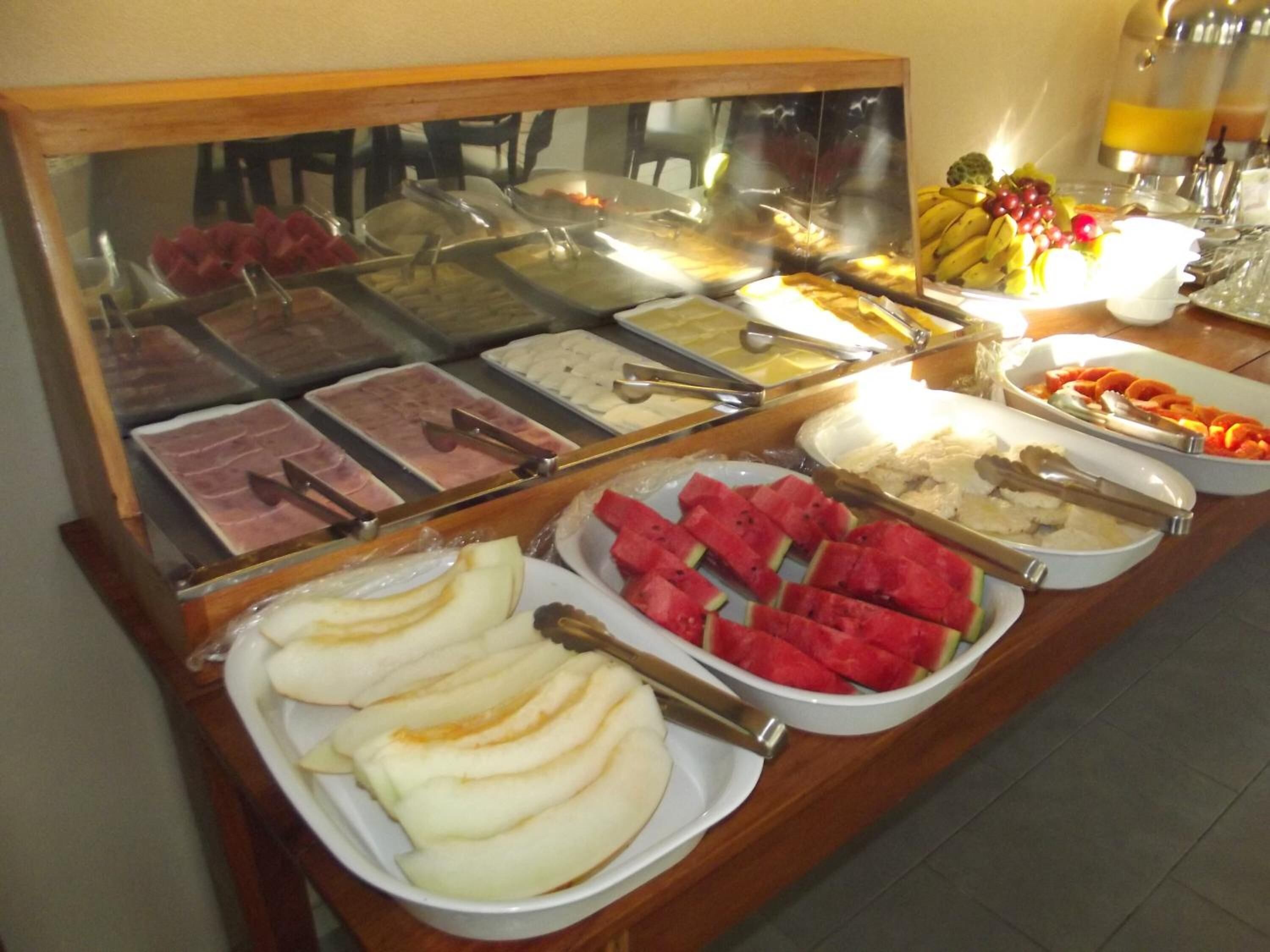 Un buffet proposant une variété de plats, notamment des fruits, des viandes et des desserts.