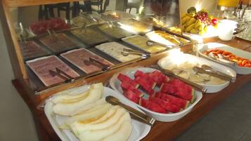 Un buffet proposant une variété de plats, notamment des fruits, des viandes et des desserts.