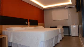 A hotel room with two beds, a desk, a chair, and a small refrigerator.