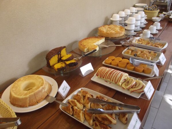 A buffet with various food items including a cake, pastries, and a variety of desserts.