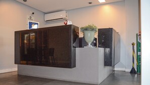 A reception desk with a dark marble top, a potted plant, and a flag.